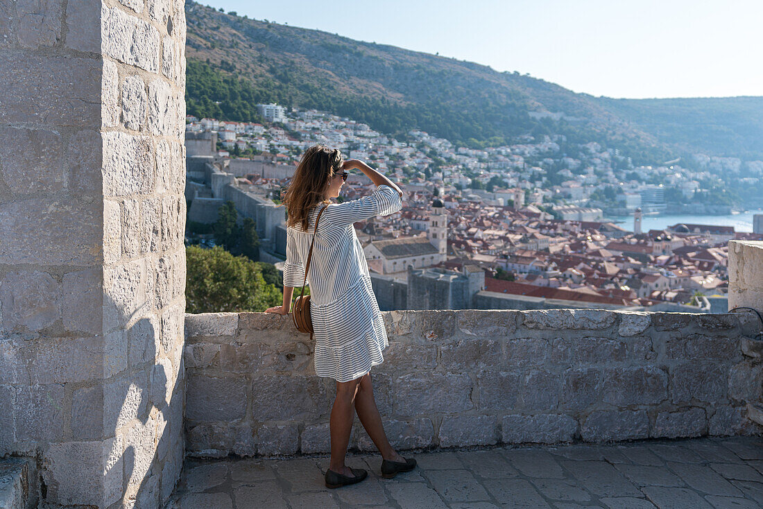 Frau blickt vom Fort Lovrijenac auf die Altstadt von Dubrovnik, Dalmatien, Kroatien.
