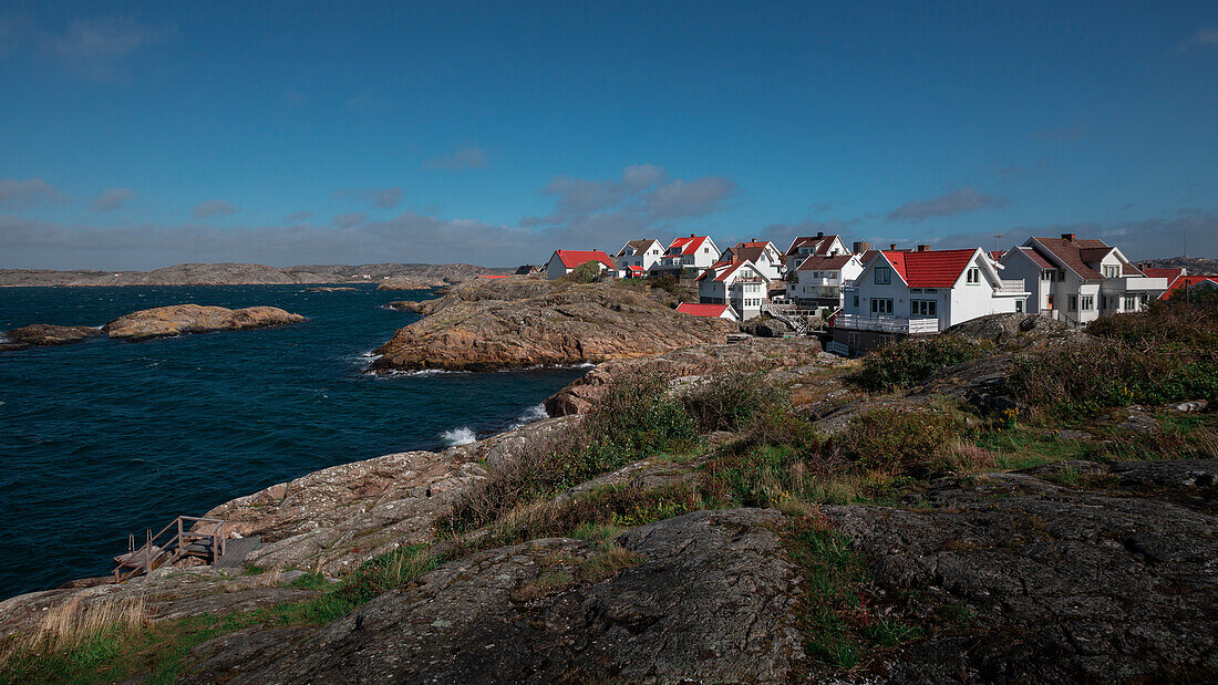 Küste mit Felsen und weißen schwedischen Häusern im Dorf Klädesholmen auf der Schäreninsel Tjörn im Westen von Schweden\n