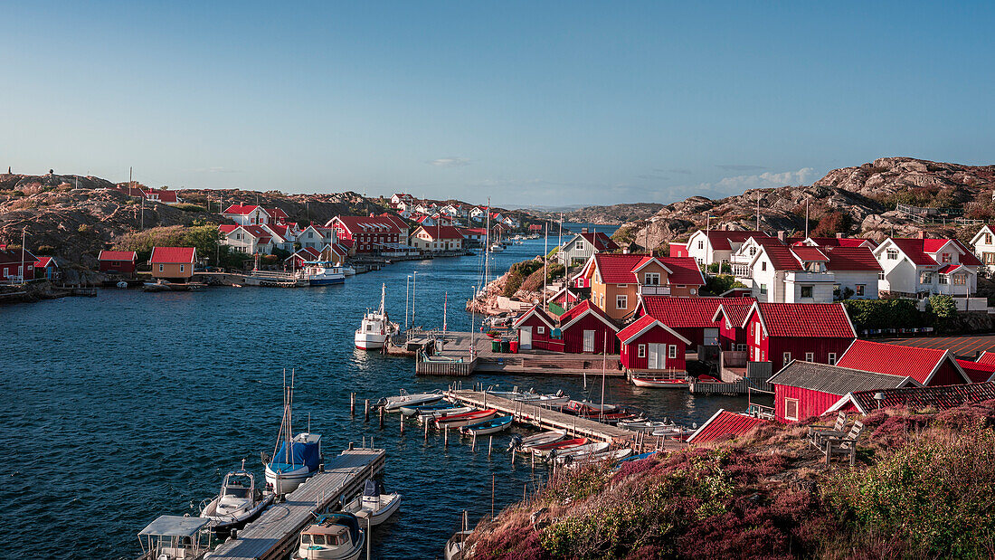 Hafen und Küste im Dorf Kyrkesund auf der Schäreninsel Tjörn an der Westküste von Schweden, blauer Himmel mit Sonne\n