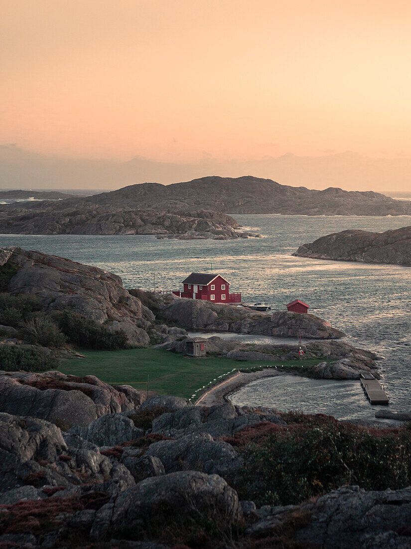 Rote Hütte an der Küste bei Skärhamn auf der Schäreninsel Tjörn an der Westküste von Schweden im Sonnenuntergang\n