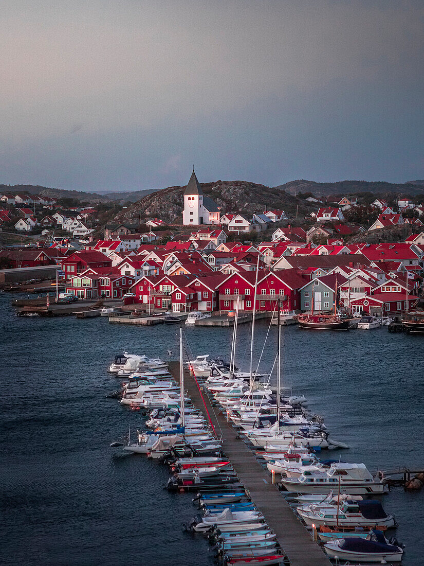 Red houses with church and boats in the harbor in the village of Skärhamn on the archipelago island of Tjörn on the west coast of Sweden, in the evening