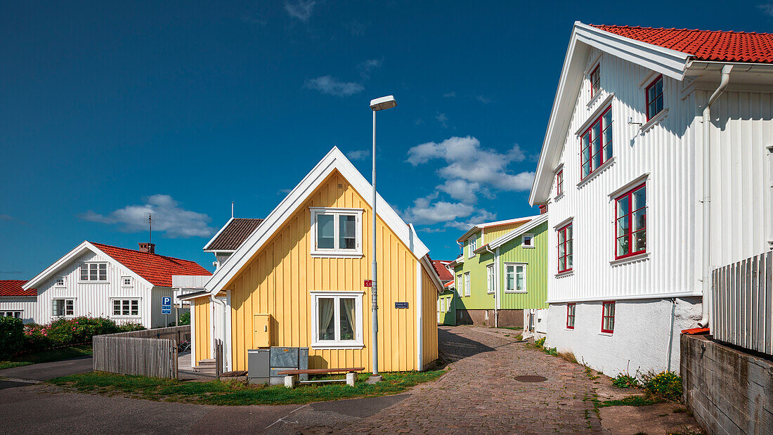 Gasse mit bunten Häusern im Dorf Mollösund auf der Schäreninsel Orust an der Westküste von Schweden, Sonne am Tag mit blauem Himmel\n