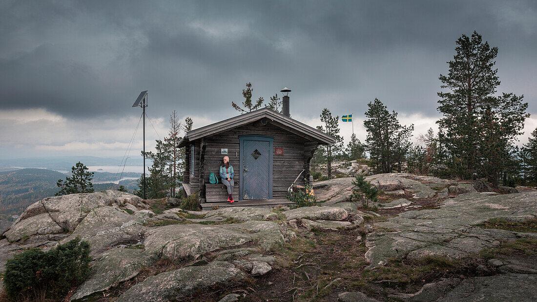 Woman sitting at a refuge on the summit of Valkallen in Höga Kusten in eastern Sweden