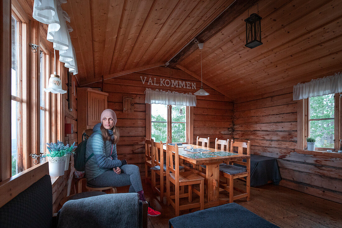 Frau sitzt in Schutzhütte auf dem Gipfel des Valkallen in Höga Kusten im Osten von Schweden\n