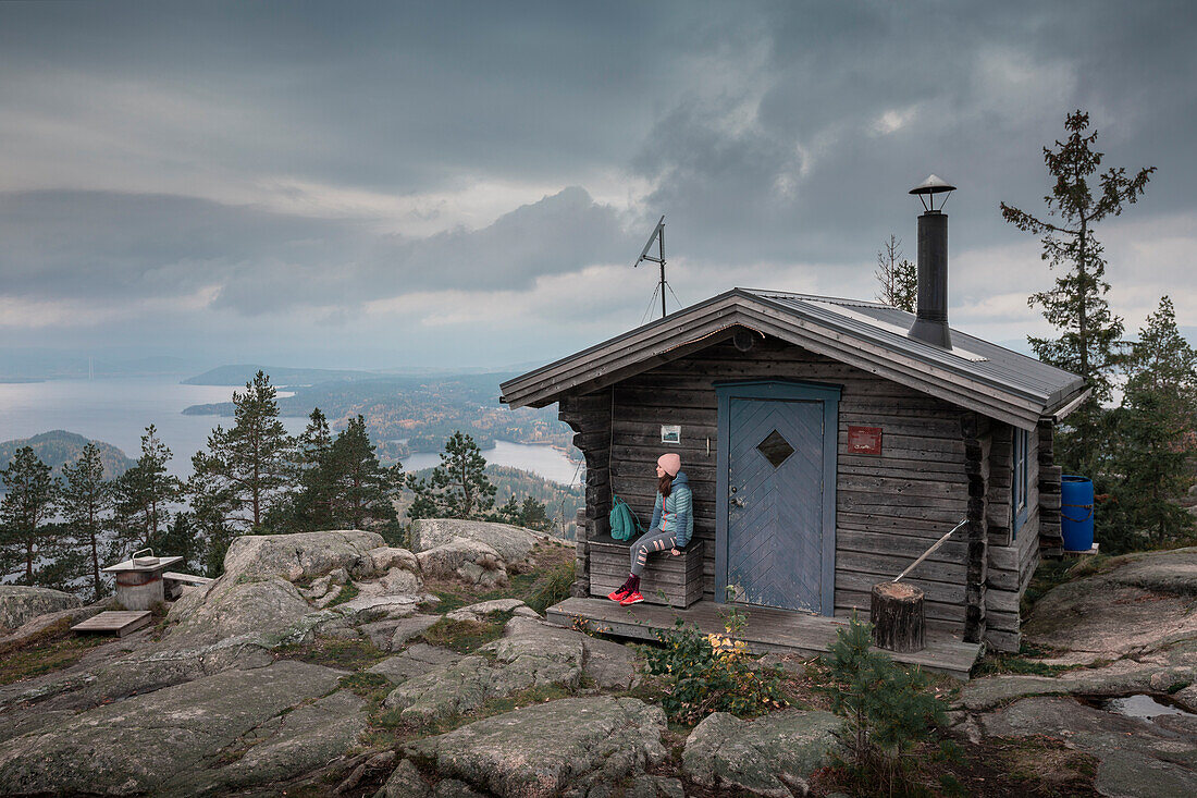 Woman sitting at a refuge on the summit of Valkallen in Höga Kusten in eastern Sweden