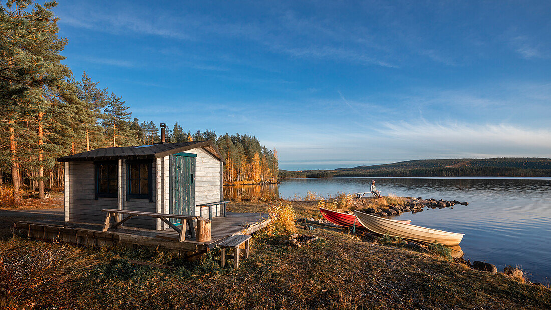 Hütte mit Booten am See in Lappland in Schweden bei Sonne mit blauem Himmel\n