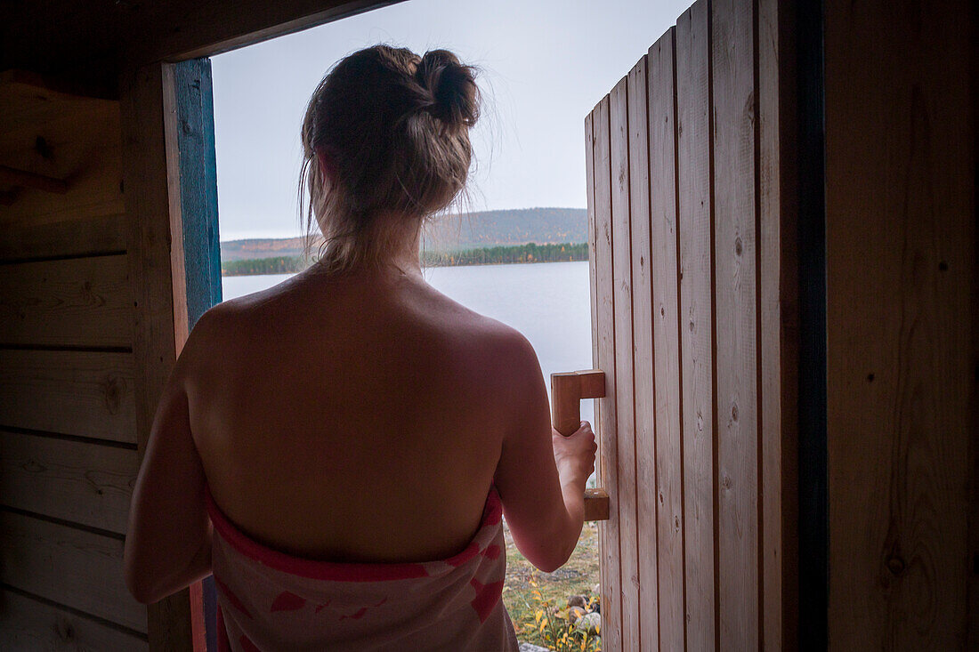 Woman leaves sauna by the lake in Lapland, Sweden