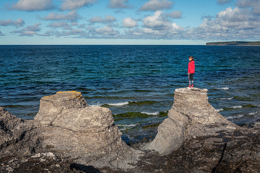 Frau an der Küste der Insel Öland auf Kalksteinfelsen in Schweden bei Sonne und blauem Himmel 