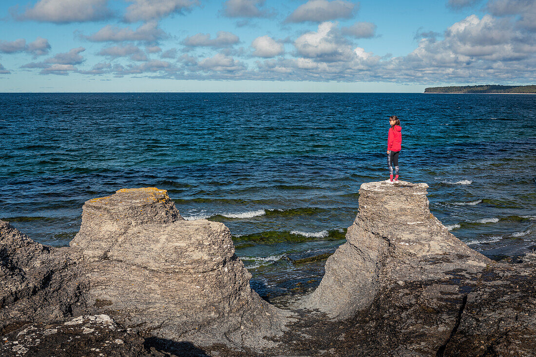 Woman on the coast of the island of Öland on limestone cliffs in Sweden with sun and blue sky