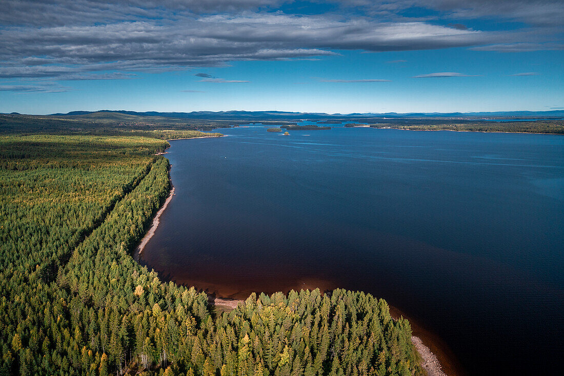 Wald und Seeufer am Siljansee von oben mit blauem Himmel in Dalarna, Schweden\n