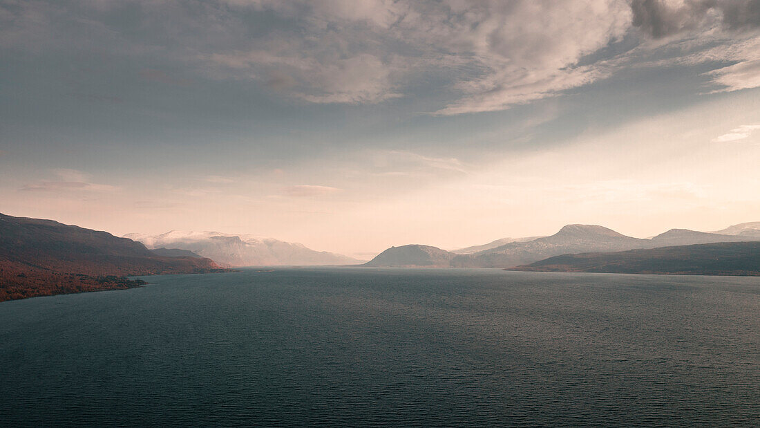 Landschaft mit Bergen und See im Stora Sjöfallet Nationalpark im Sonnenuntergang in Lappland in Schweden\n