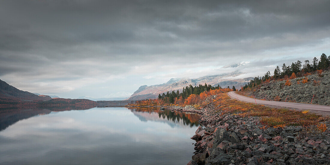 Straße in die Landschaft mit Bergen und See im Stora Sjöfallet Nationalpark im Herbst in Lappland in Schweden\n