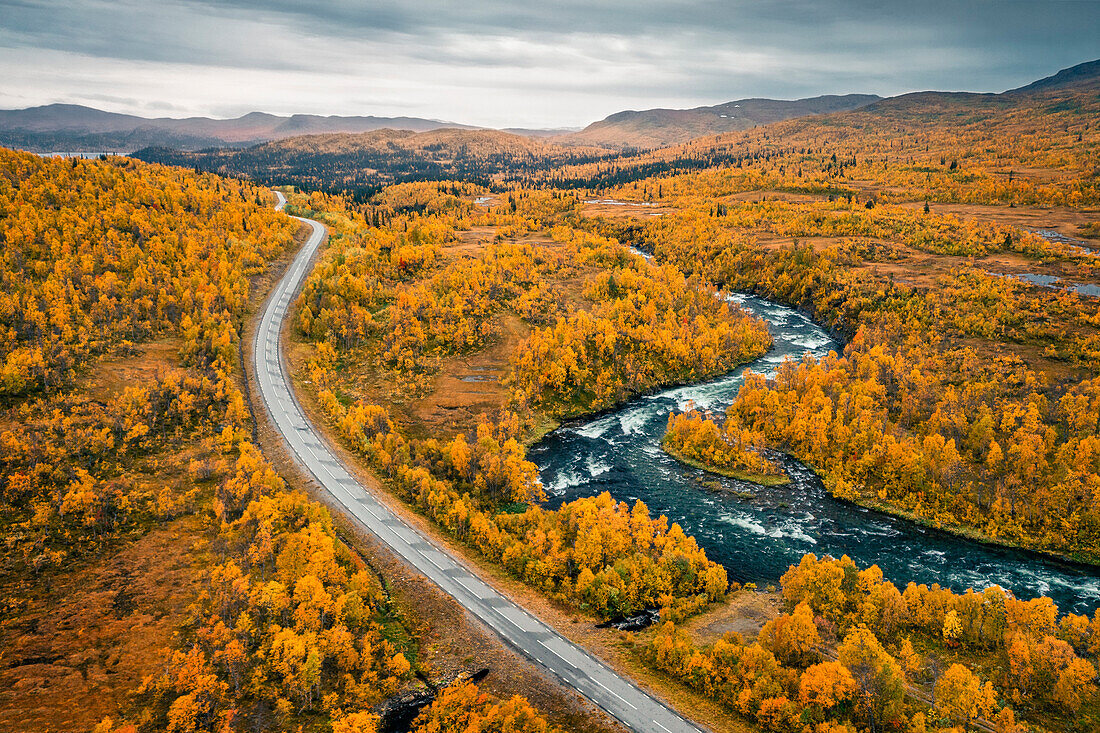 Panoramic Wilderness Road along a river, with mountains and trees in autumn in Jämtland in Sweden from above