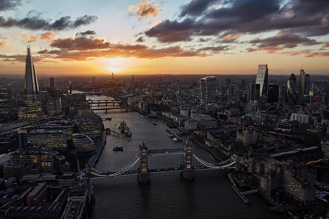 Großbritannien, London, Luftaufnahme der Tower Bridge und des Finanzviertels bei Sonnenuntergang