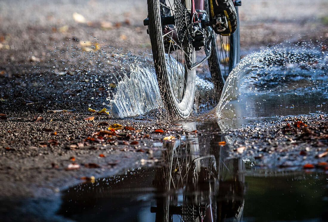 Autumn weather. Gravel biker drives through puddle
