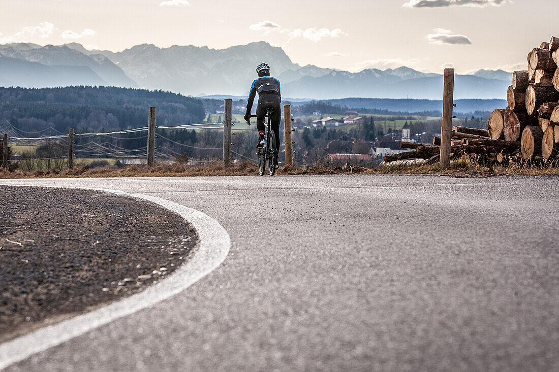 Racing cyclists on the Ludwigshöhe near Deining, Prealps. Mountain panorama with Zugspitze