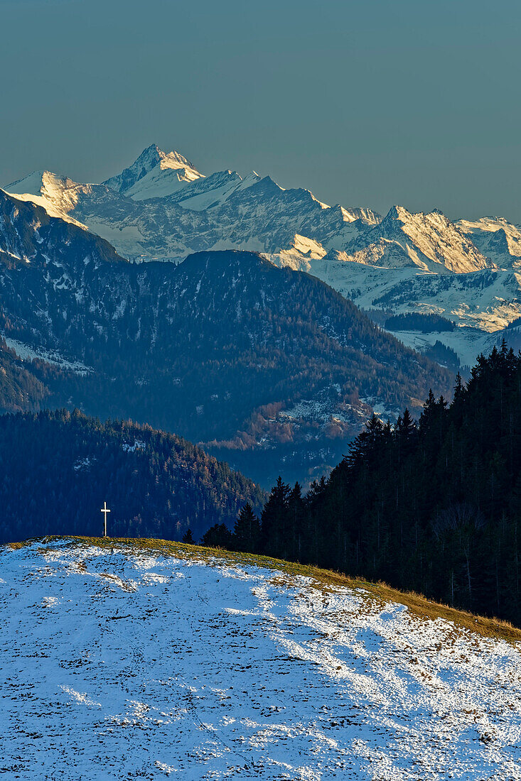 Snow-covered meadow ridge with summit cross in front of Hohe Tauern with Grossglockner, Mangfall Mountains, Bavarian Alps, Upper Bavaria, Bavaria, Germany