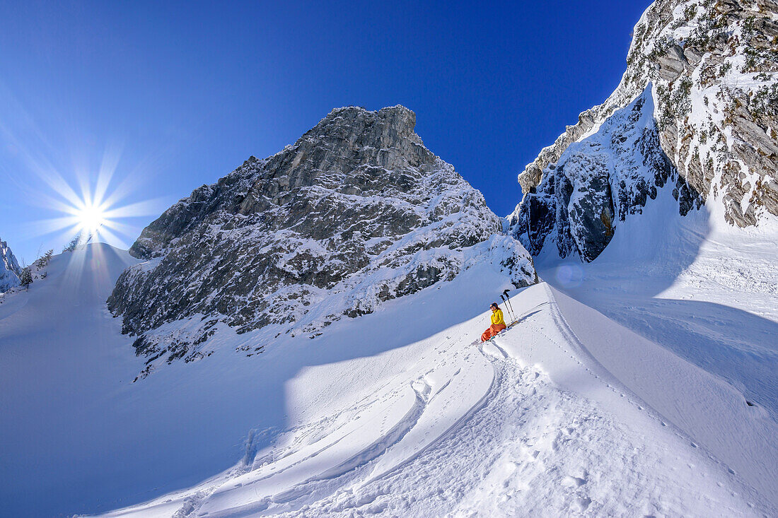 Frau auf Skitour macht unter großem Felswänden Pause, Zwiesel, Chiemgauer Alpen, Oberbayern, Bayern, Deutschland