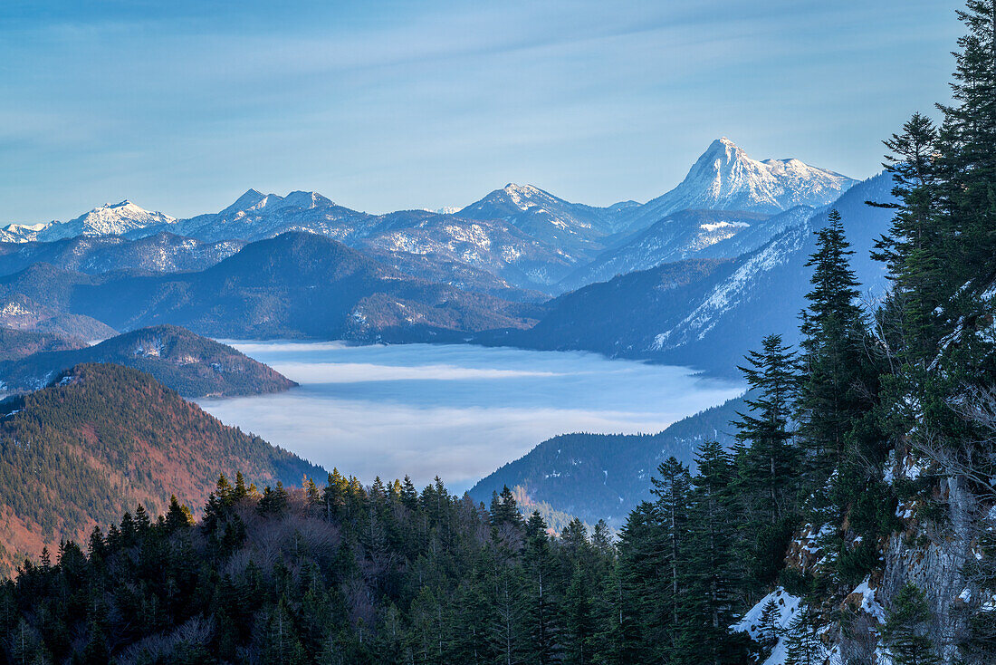 Short rest on the way to the Herzogstand in winter with a view of the Guffert and adjacent peaks, Bavarian Alps, Bavaria, Germany