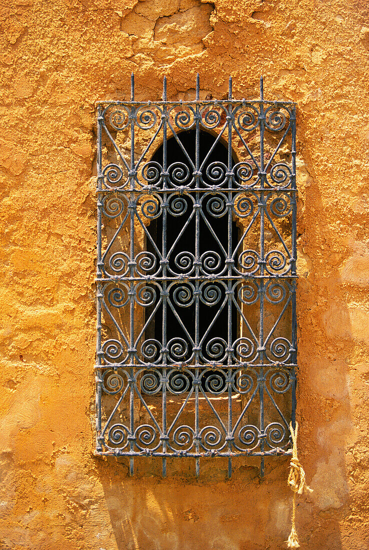 Ornate ironwork on arched window on stucco wall, Marrakesh, Morocco