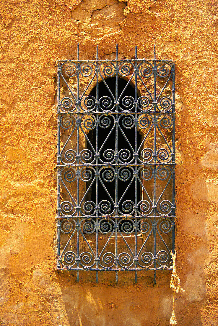 Reich verzierte Schmiedearbeiten am Rundbogenfenster an der Stuckwand, Marrakesch, Marokko