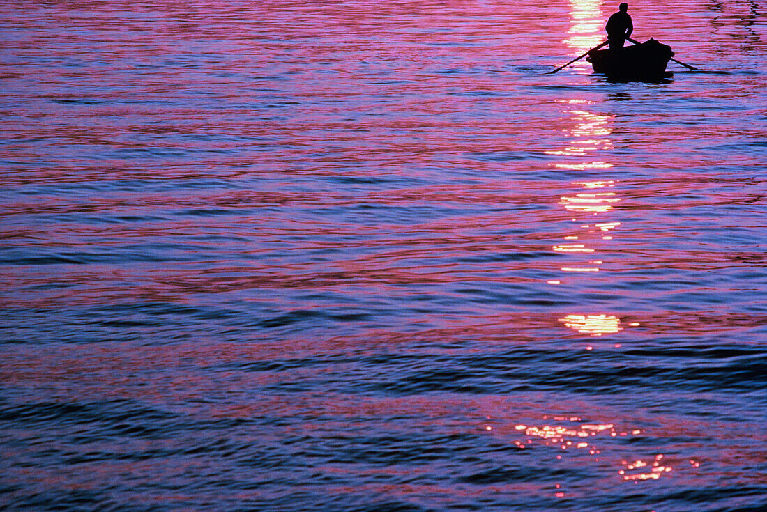 Silhouette of a person in boat at sunset, Anzio, Italy