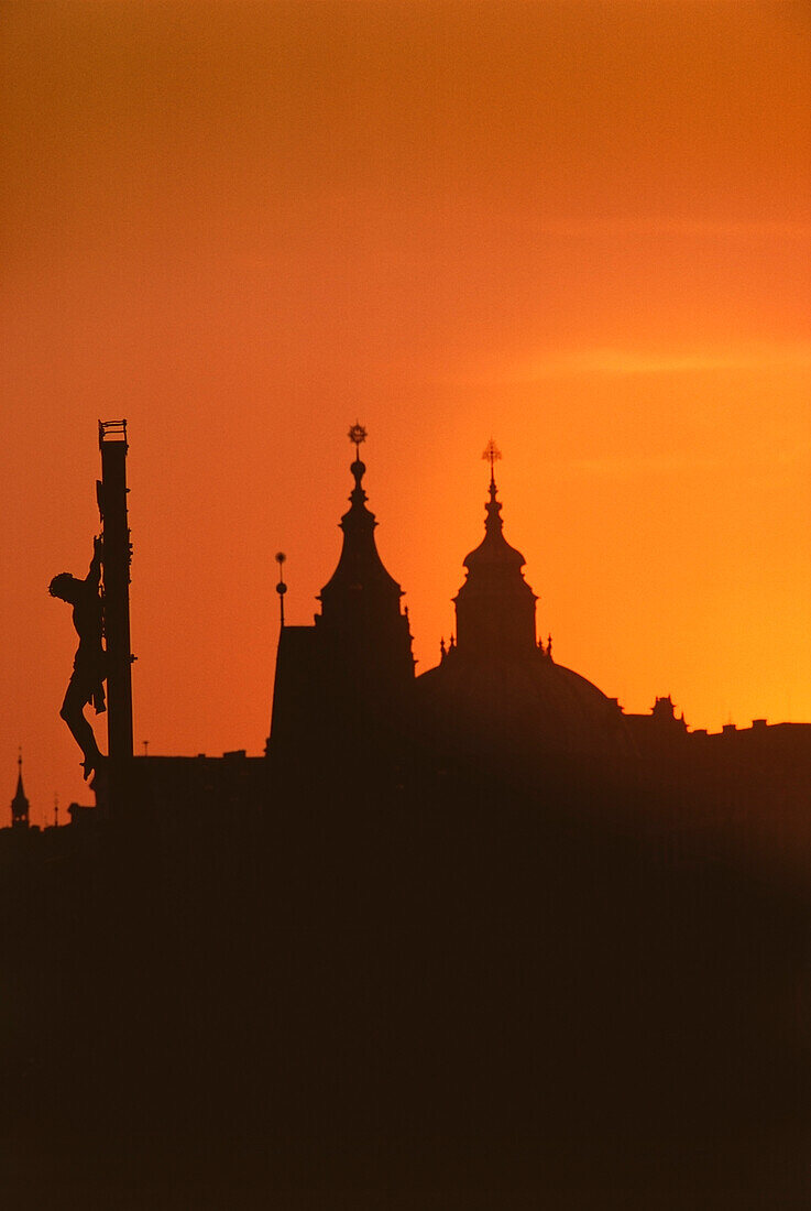Silhouette der Statue von Jesus Christus und der Kathedrale bei Sonnenuntergang, Karlsbrücke, Prag, Tschechische Republik