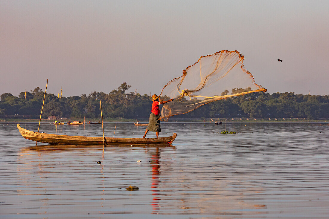 Ein Fischer wirft auf dem Taungthaman-See bei Mandalay in Myanmar ein Netz aus