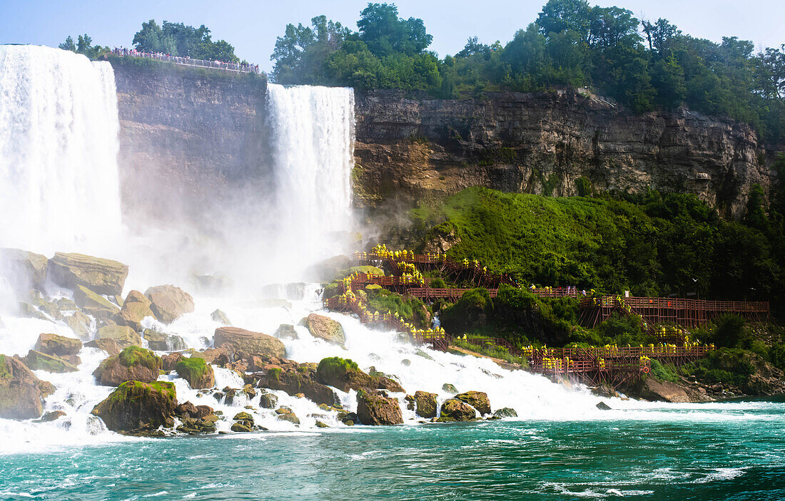 Menschen in gelben Regenmänteln an den Bridal Veil Falls von Niagara Falls, Ontario, Kanada aus gesehen