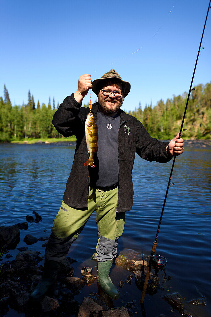 At Rupkivi characteristic rock in Savinajoki river, anglers on Bear Circle hiking trail, perch on hook, Finland