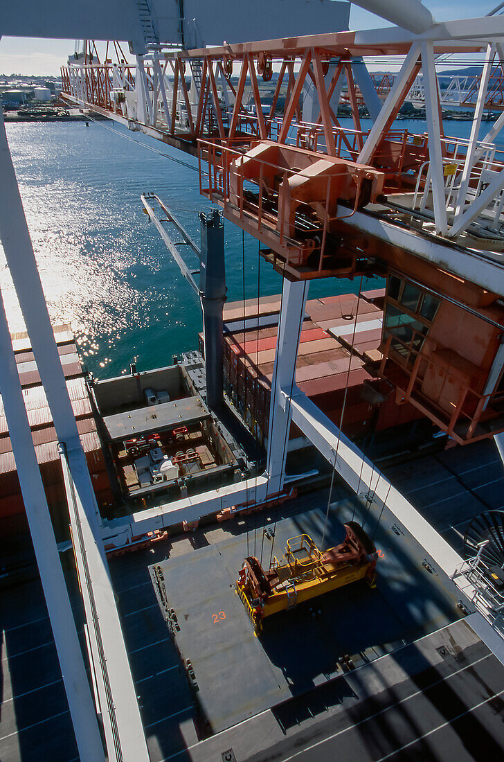 Looking from top of crane as it secures a shipping container to load onto ship
