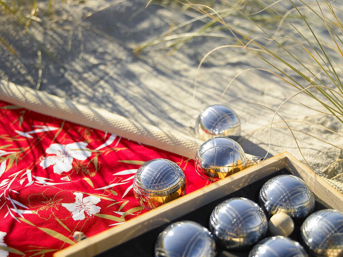 Petanque balls on bright mat and sand at the beach