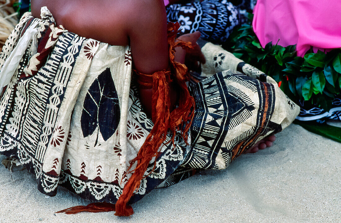 Rückansicht männlicher Fidschi-Tänzer in traditioneller Kleidung, die auf dem Boden sitzen