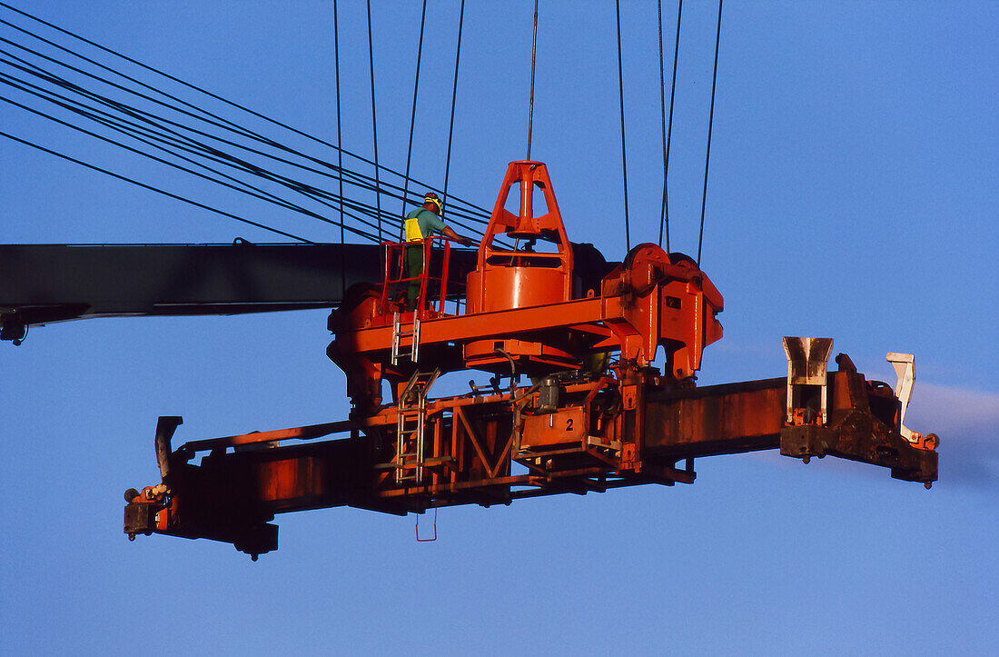 Mann, der einen Kran zum Be- und Entladen von Schiffscontainern im Hafen bedient