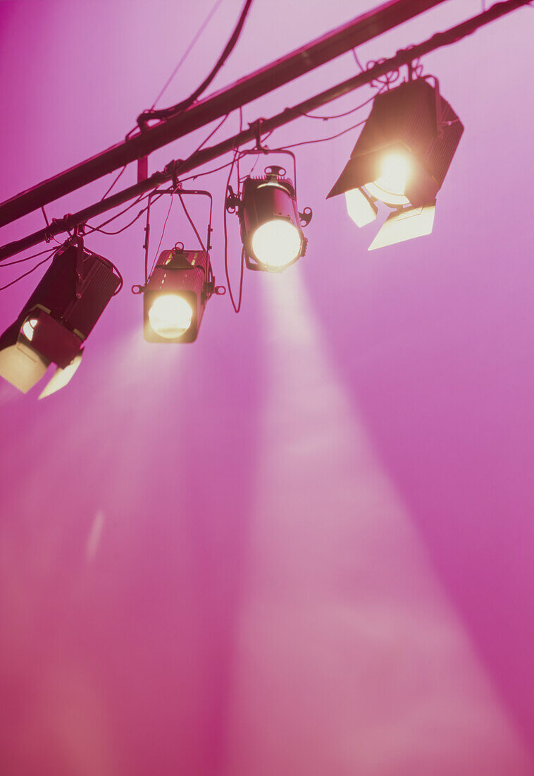 Spotlights shining downwards against pink background