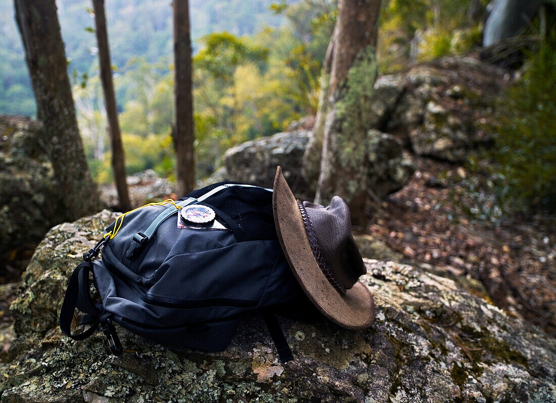 Kompass, Rucksack und australischer Akubra-Hut ruhen auf einem Felsen im australischen Busch