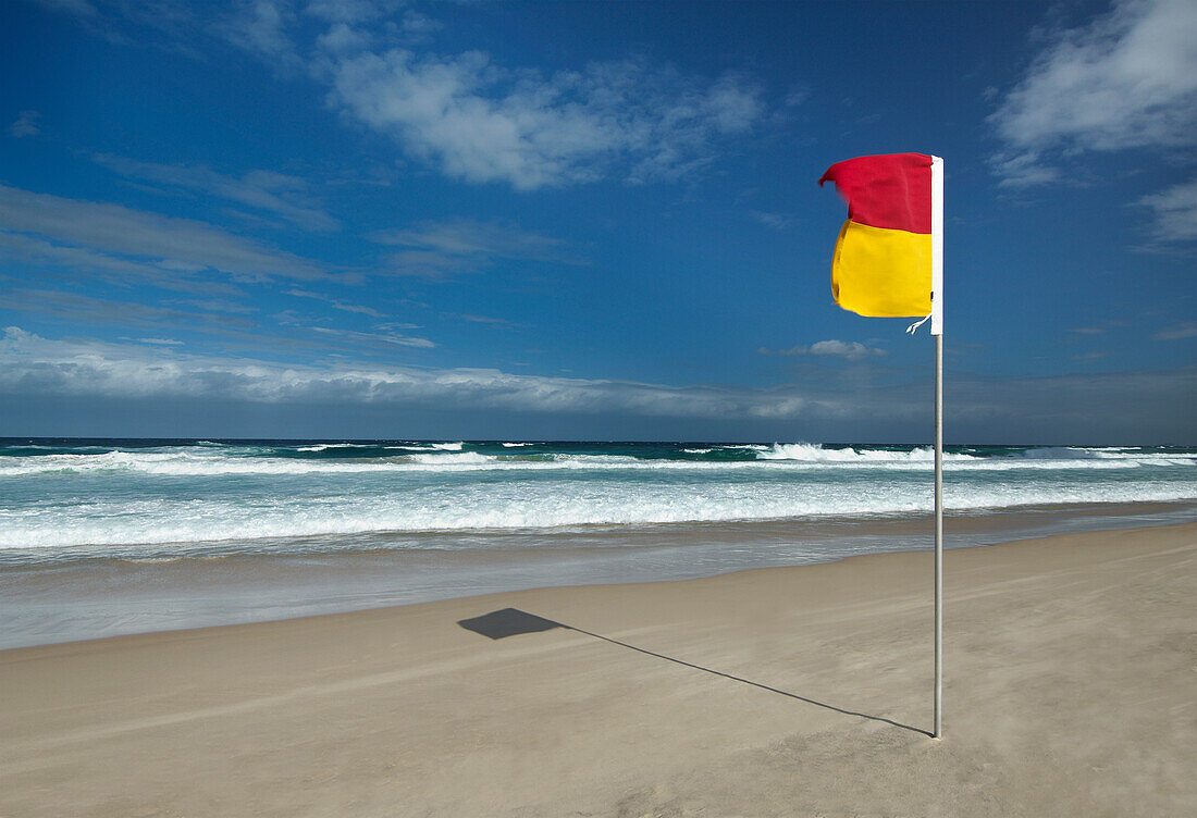 Rote und gelbe Brandungsfahne am Strand in Australien