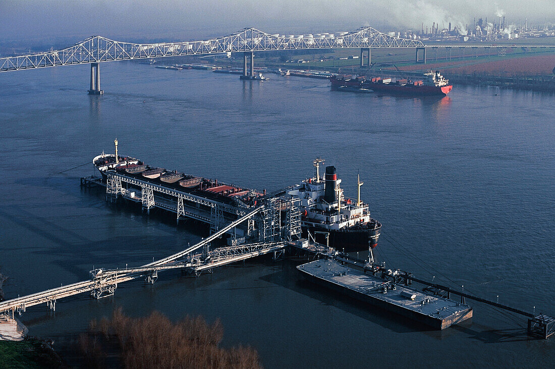 Ship docked in a river near a chemical plant, Mississippi River, Mississippi, USA