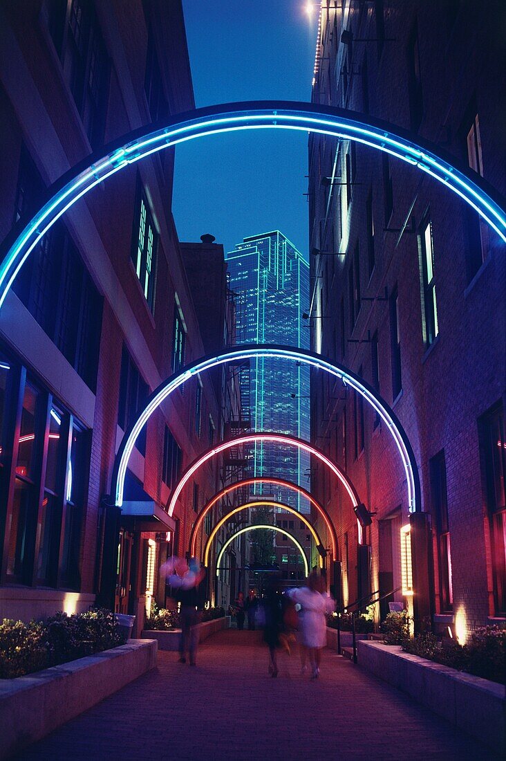 Neon beleuchteter Torbogen in einer Gasse im historischen Viertel West End mit Bank of America Building im Hintergrund, Dallas, Texas, USA