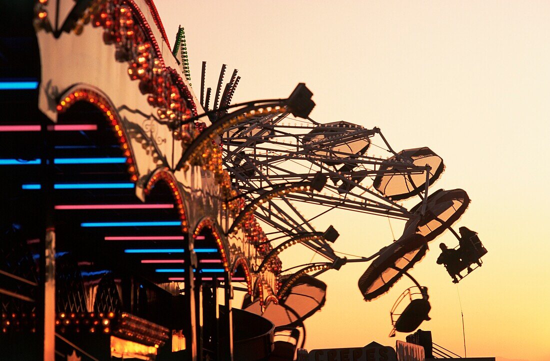 Menschen, die einen Karnevalsweg fahren, fahren bei Sonnenuntergang auf der Texas State Fair, Dallas, Texas, USA