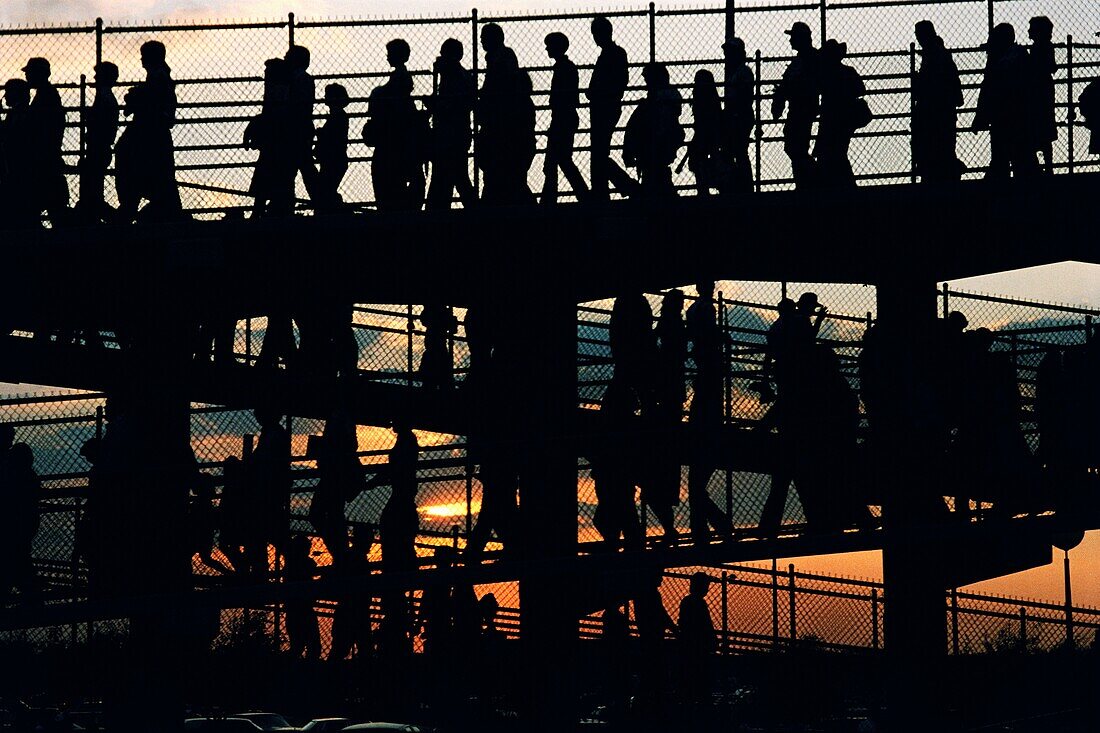 Silhouette von Menschen, die bei Sonnenuntergang eine Rampe hinuntergehen