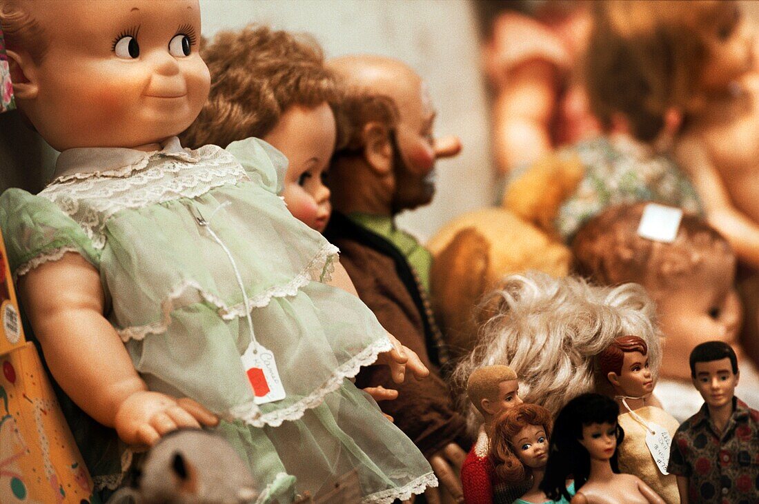 Sammlung von Vintage-Puppen, Barbie-Puppen und einer Clown-Puppe in einem Schaufenster
