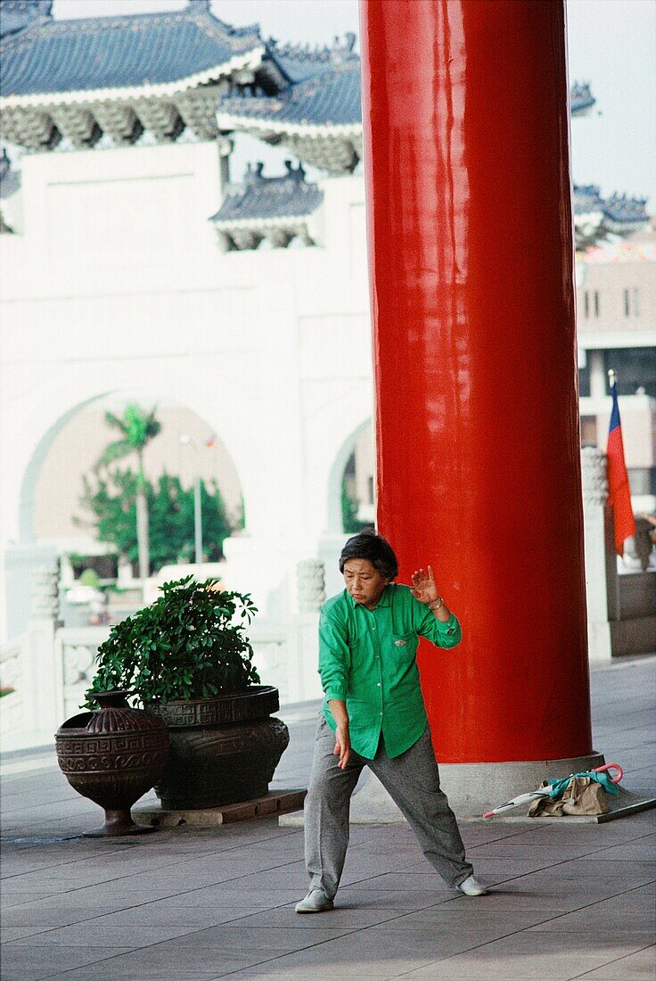 Woman doing Tai Chi near a red column of the National Theater, Taipei, Taiwan