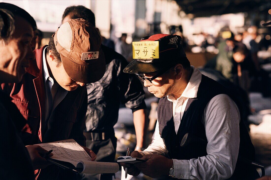 Fish vendor reviewing paperwork for an order at Tsukiji Fish Market, Tokyo, Japan