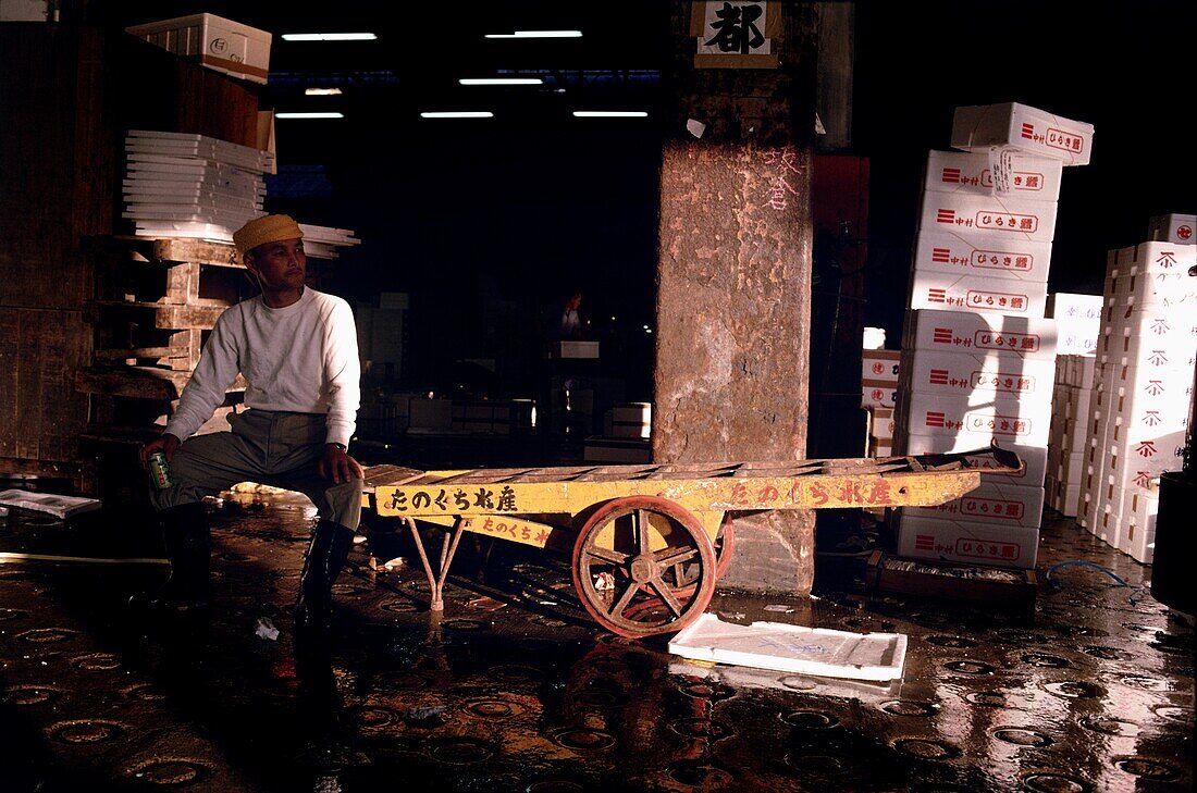 Mann sitzt an der Laderampe des Fischmarktes Tsukiji, Tokio, Japan