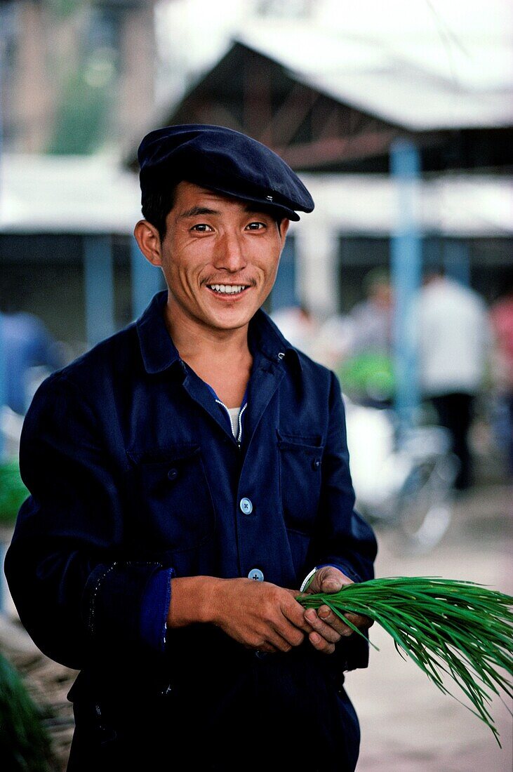 Portrait of a man holding a bunch of chives, China