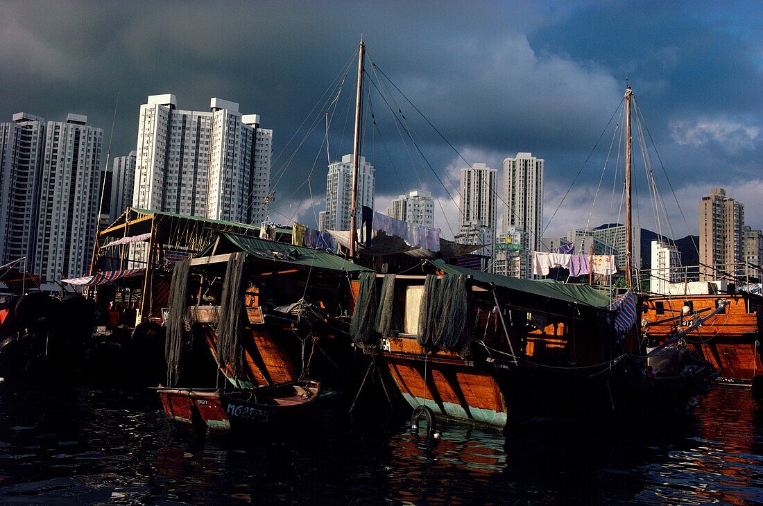 Dschunken angedockt an der Uferpromenade mit Wolkenkratzern im Hintergrund, Hongkong