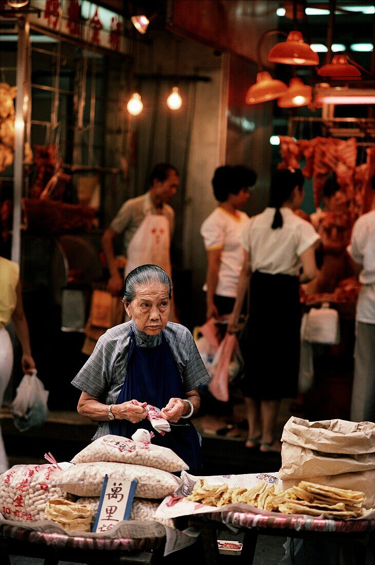 Frau, die Lebensmittel auf einem Straßenmarkt in Hongkong verkauft