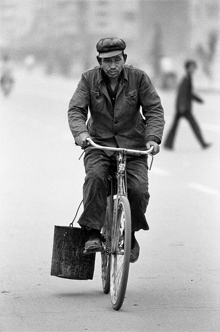 China, Datong, Mann Reiten Fahrrad mit Eimer