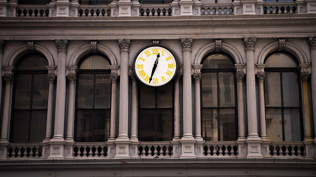 Eine traditionelle analoge Uhr mit gelben Zahlen auf der Vorderseite eines alten Bürogebäudes in SoHo, Manhattan, New York.